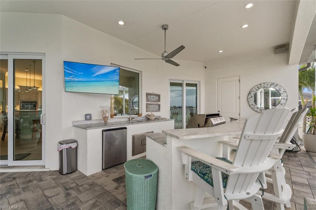 Expansive outdoor kitchen featuring a built-in grill, sink, and under-counter refrigeration