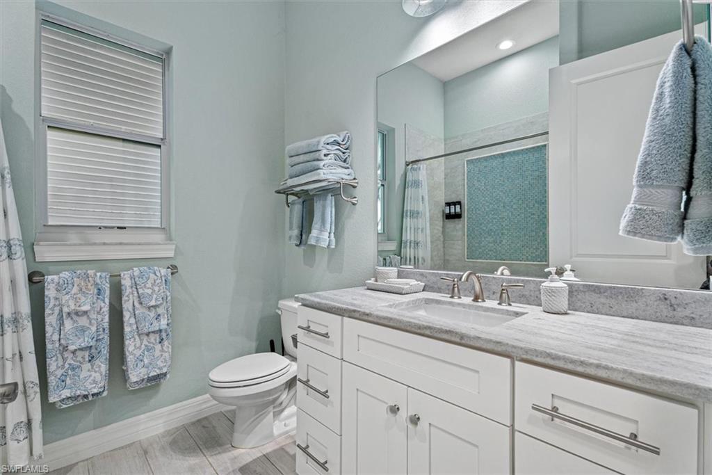 Modern bathroom featuring a single vanity with stone countertop, undermount sink, and brushed nickel hardware