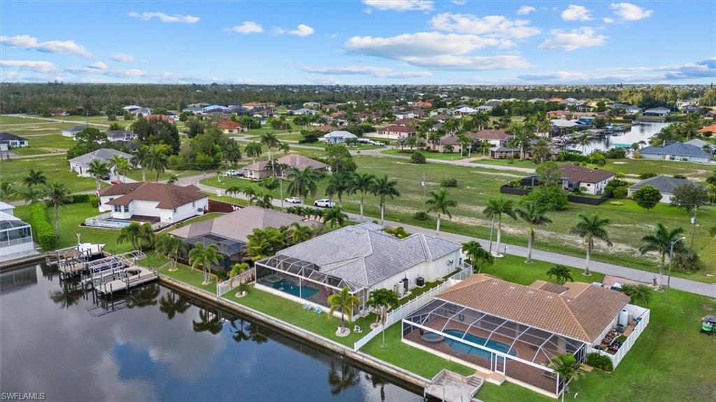 Waterfront property featuring a private boat dock, screened-in pool enclosure, mature palm trees, and canal access