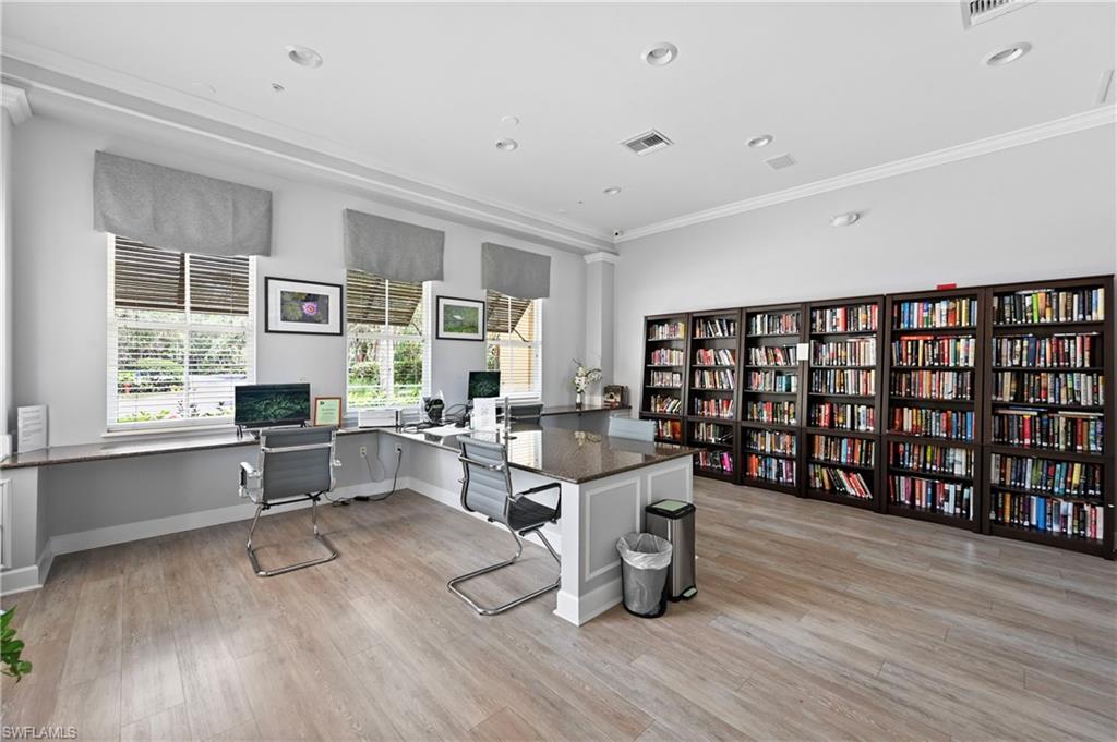Spacious library featuring built-in bookcases, wood-finish flooring, recessed lighting, and crown molding