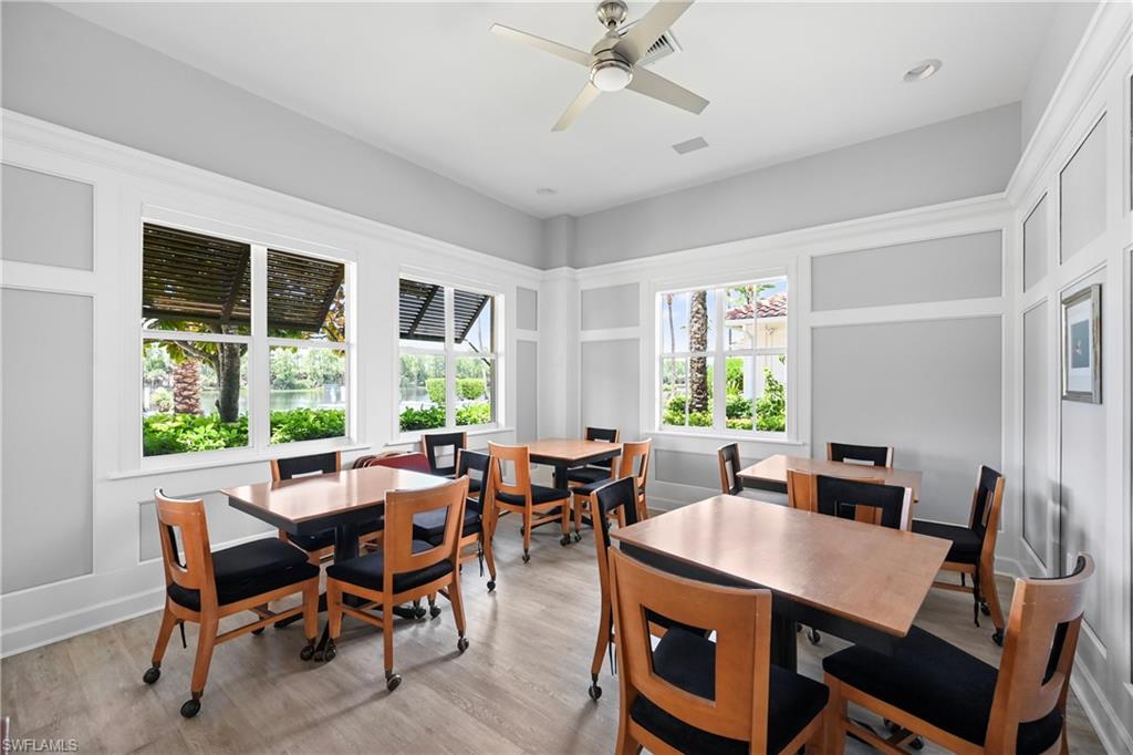Room featuring light wood-finish flooring, white paneling, multiple windows, a ceiling fan, and recessed lighting
