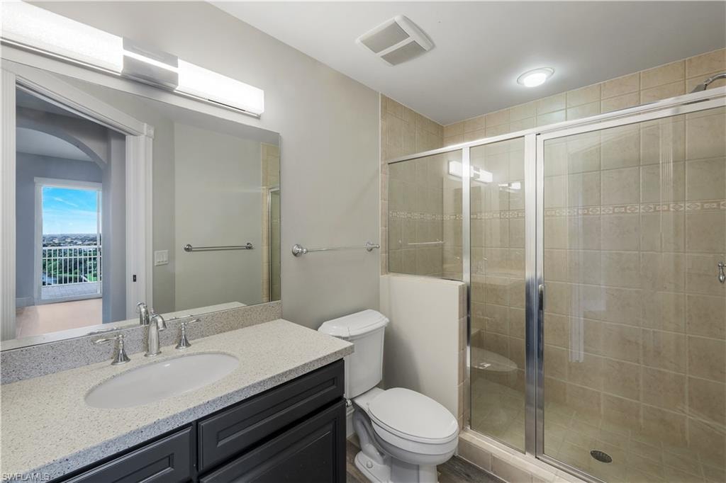 En suite bathroom for bedroom #2 featuring a single vanity with dark cabinetry, a light speckled countertop, and an oval undermount sink