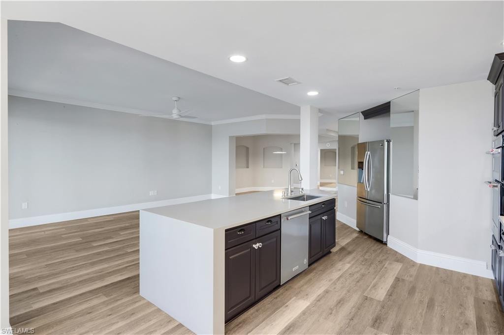 Open-concept kitchen featuring a large island, stainless steel sink, and integrated dishwasher