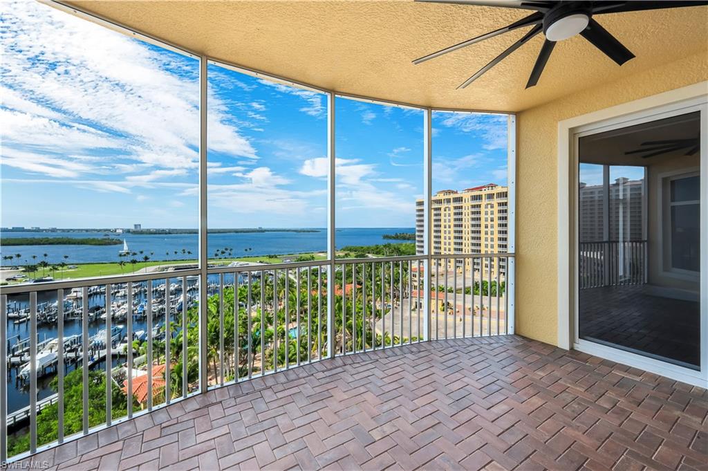 Rear, screened balcony featuring marina views, brick-patterned flooring, a ceiling fan, and sliding glass doors into the primary suite and to the living room.