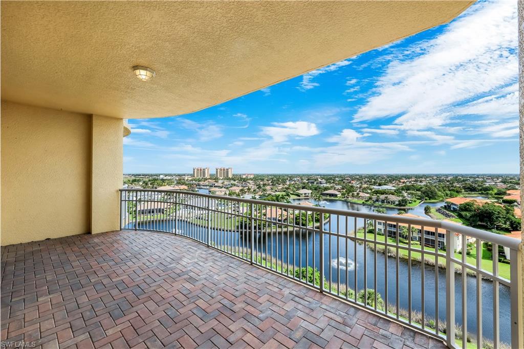 Expansive front, curved balcony featuring fountain and neighborhood views, brick paver flooring and sliding glass doors leading into BR2, Den, and BR3