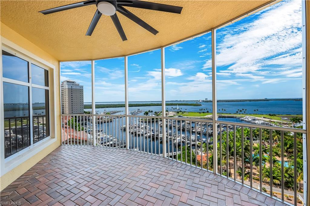 Rear, screened balcony featuring marina views, brick-patterned flooring, a ceiling fan, and sliding glass doors into the primary suite and to the living room.