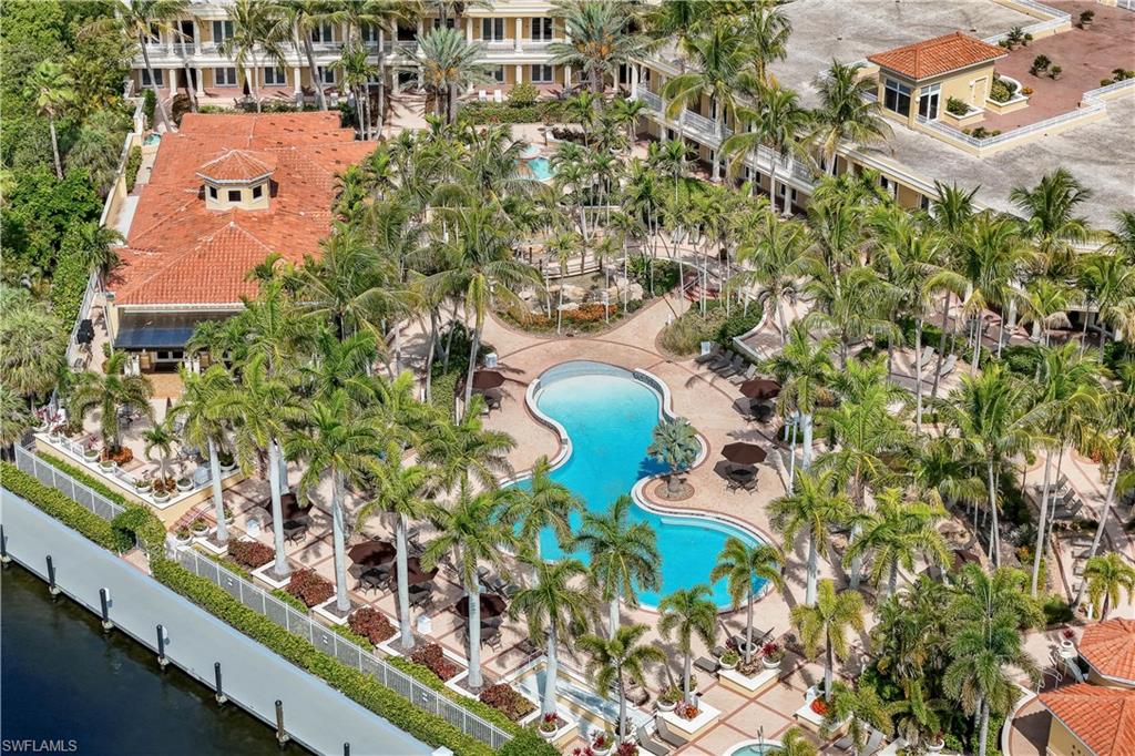 Expansive resort-style grounds featuring a large freeform swimming pool, extensive palm tree landscaping, and paved walkways