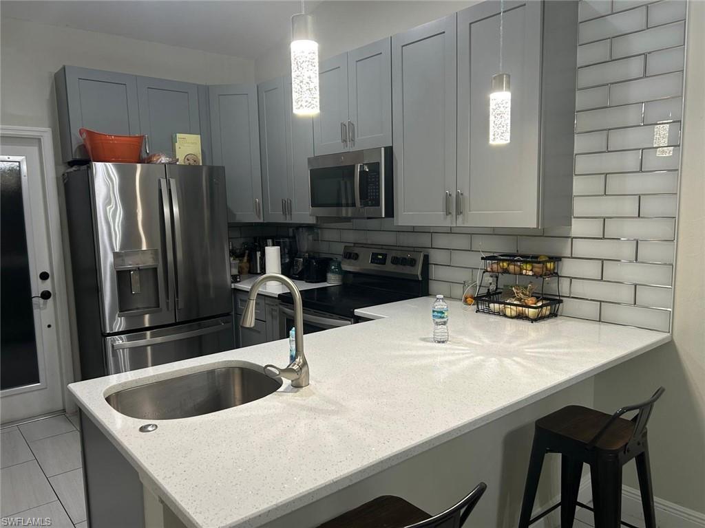 Contemporary kitchen featuring light gray cabinetry, stainless steel appliances, and a white subway tile backsplash
