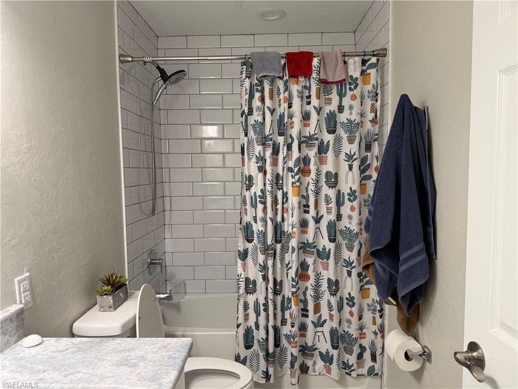 Bathtub and shower combination featuring white subway tile surround, polished chrome shower fixtures, and a recessed ceiling light