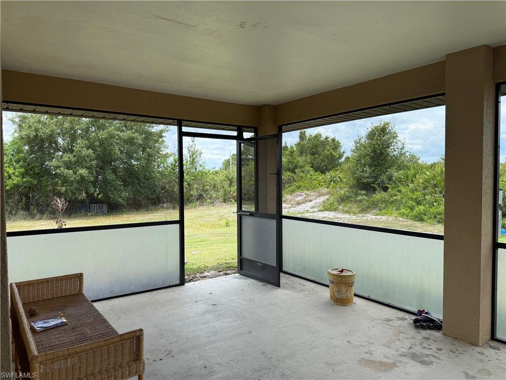 Screened lanai featuring a concrete floor, opaque lower screening, and a screened entry door