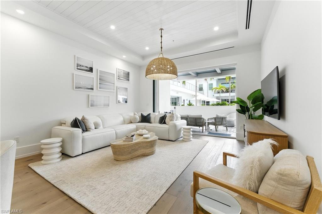 Living room with light wood floors, recessed lighting, wood ceiling, and a tray ceiling