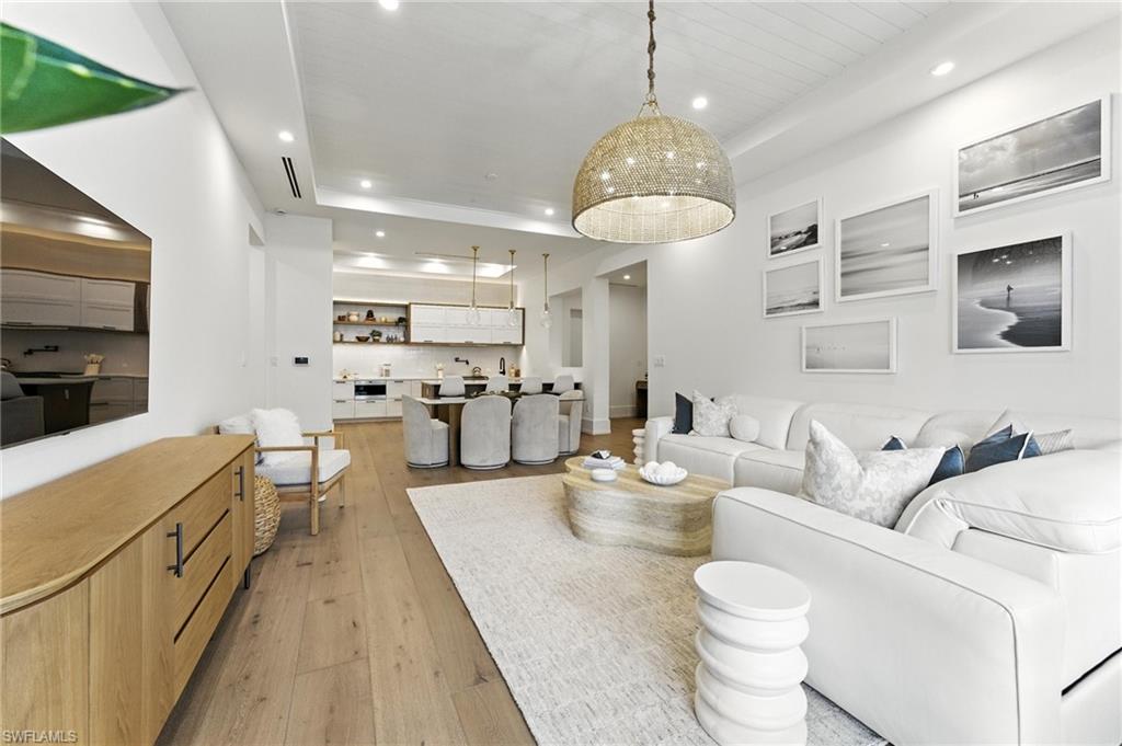 Living room featuring recessed lighting, light wood-style flooring, and a tray ceiling