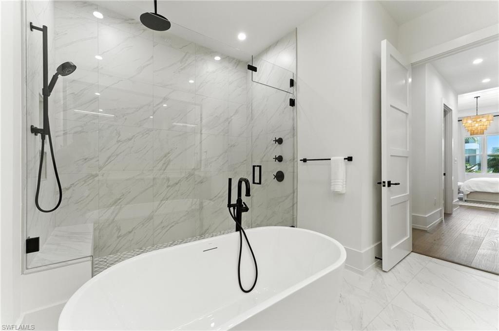Ensuite bathroom featuring recessed lighting, a freestanding tub, a marble finish shower, and marble finish floors