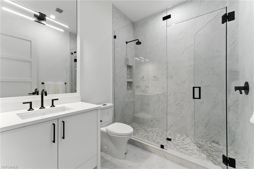 Bathroom with marble finish flooring, vanity, and a marble finish shower