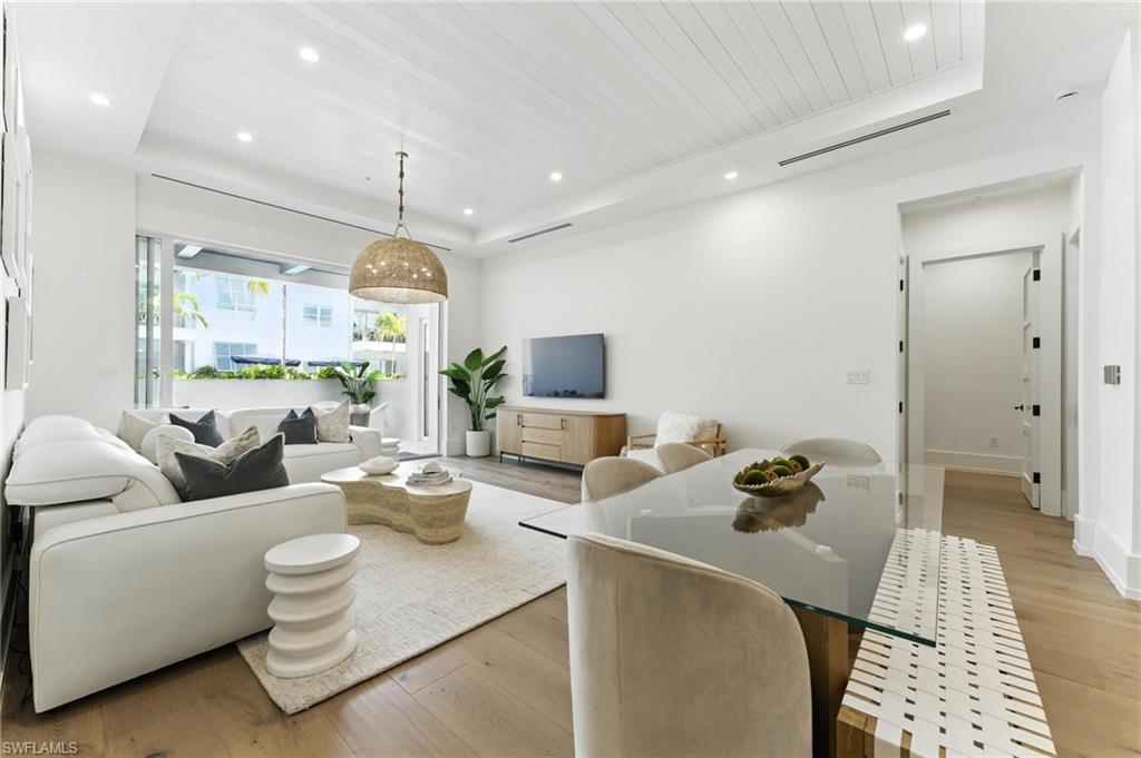 Living area with a raised ceiling, light wood-style floors, recessed lighting, and wooden ceiling