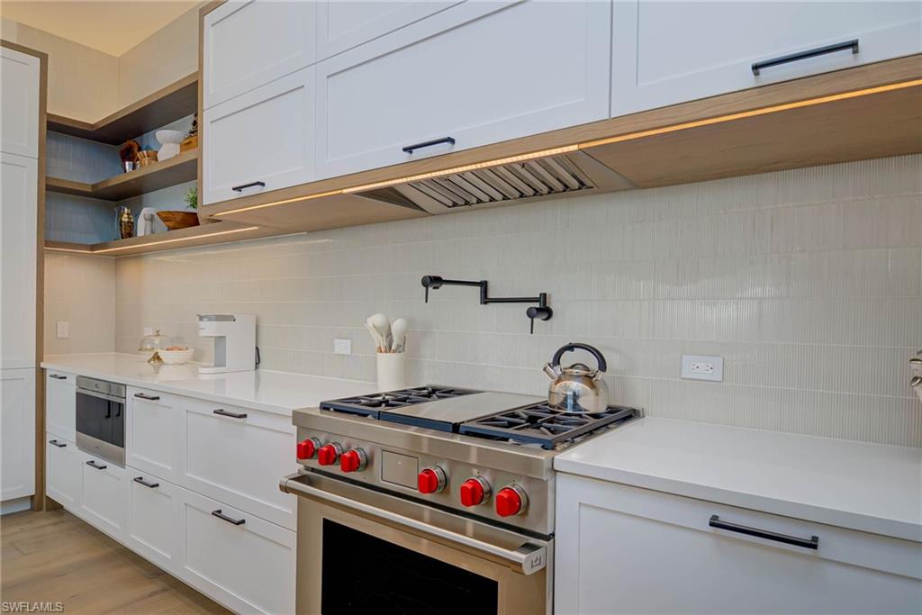 Kitchen featuring stainless steel range, backsplash, and light countertops