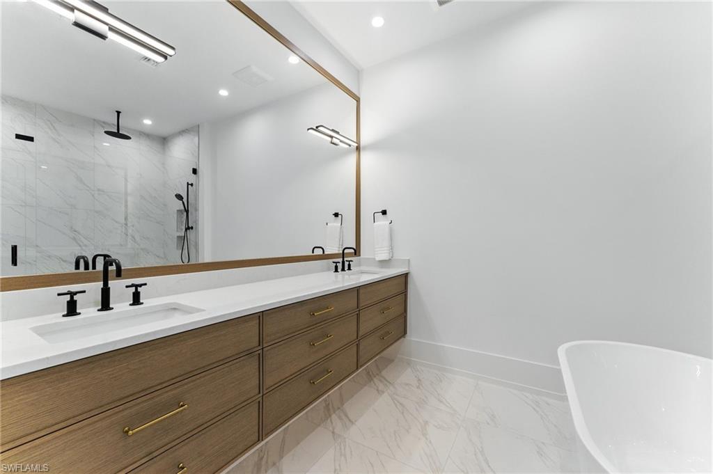 Bathroom featuring a marble finish shower, double vanity, marble finish floors, a freestanding tub, and recessed lighting
