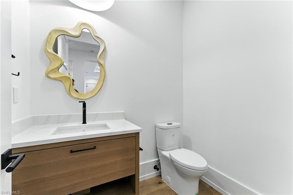 Half bath featuring vanity and wood finished floors just off the entry