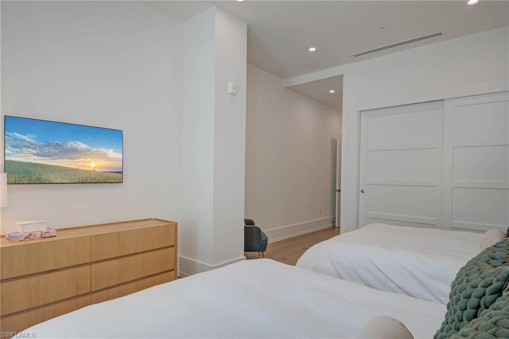 Bedroom with wood finished floors, recessed lighting, and a closet