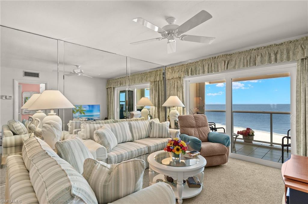 Living area featuring a sliding glass door to an exterior balcony, a ceiling fan, mirrored wall panels, and carpet flooring