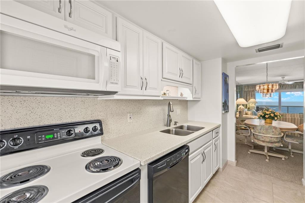 Kitchen featuring white cabinetry, light-toned countertops, a double basin stainless steel sink, and a built-in microwave