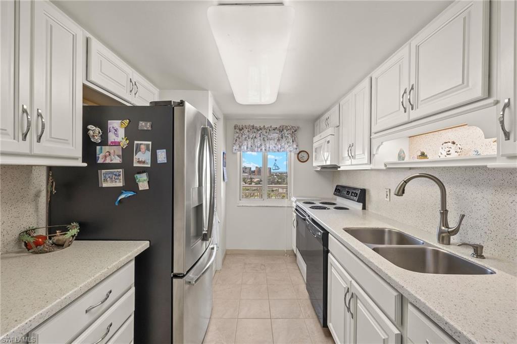 Galley kitchen featuring white cabinetry, light-toned countertops, and a full suite of appliances
