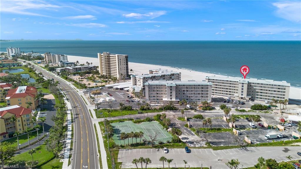 Beachfront condominium building with direct beach access, multiple balconies, and onsite tennis courts