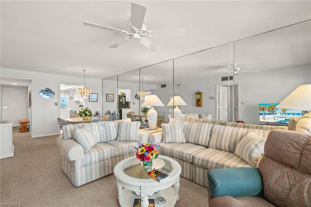 Bright living space featuring wall-to-wall mirroring and light-toned carpeting