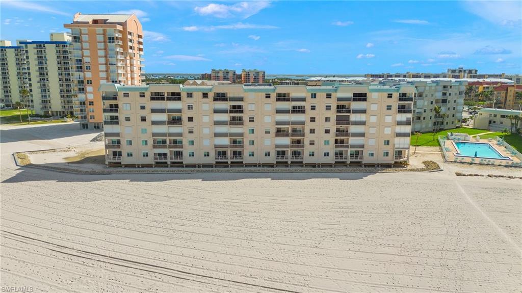 Multi-story residential building featuring private balconies overlooking a sandy beachfront