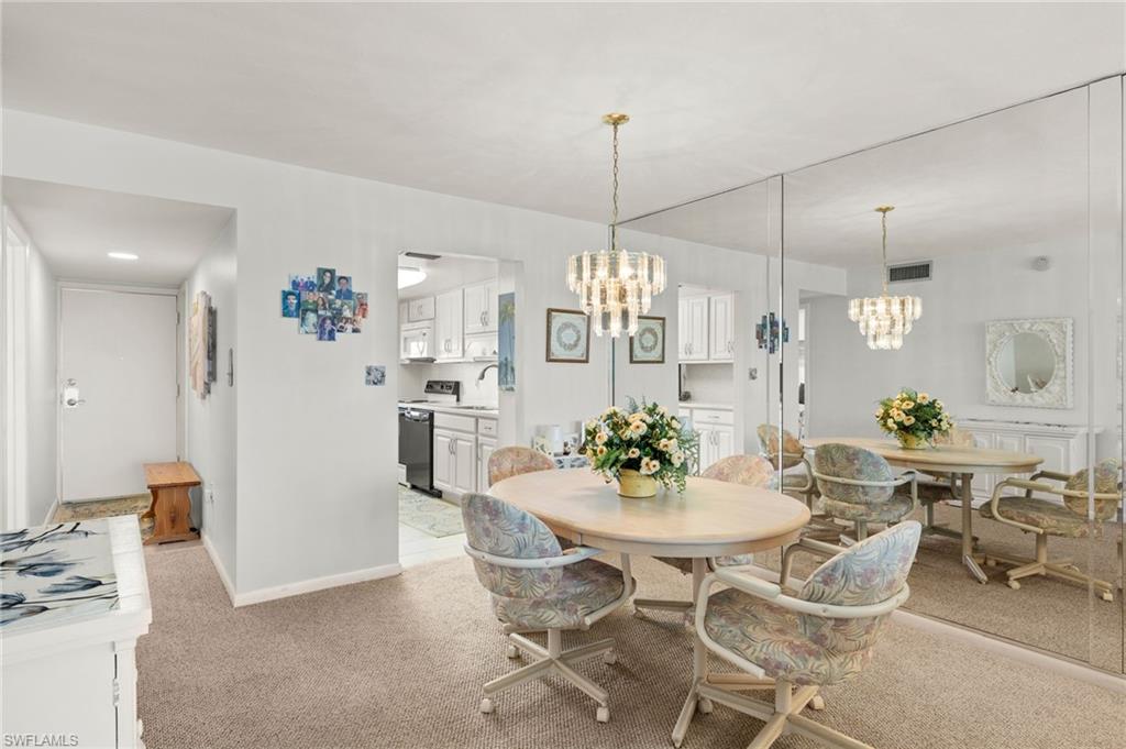 Dining area with full-wall mirror, carpeted flooring, and a crystal-style chandelier