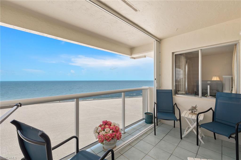 Enclosed balcony featuring a tiled floor, glass railings, and expansive ocean frontage