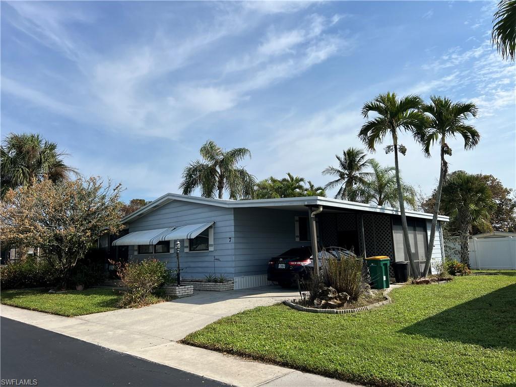 View of front of property with a front yard and a carport