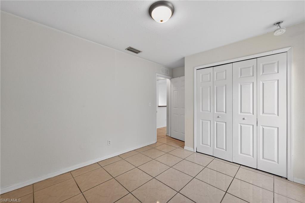 Neutral tone tile flooring, white walls, and a ceiling-mounted light fixture