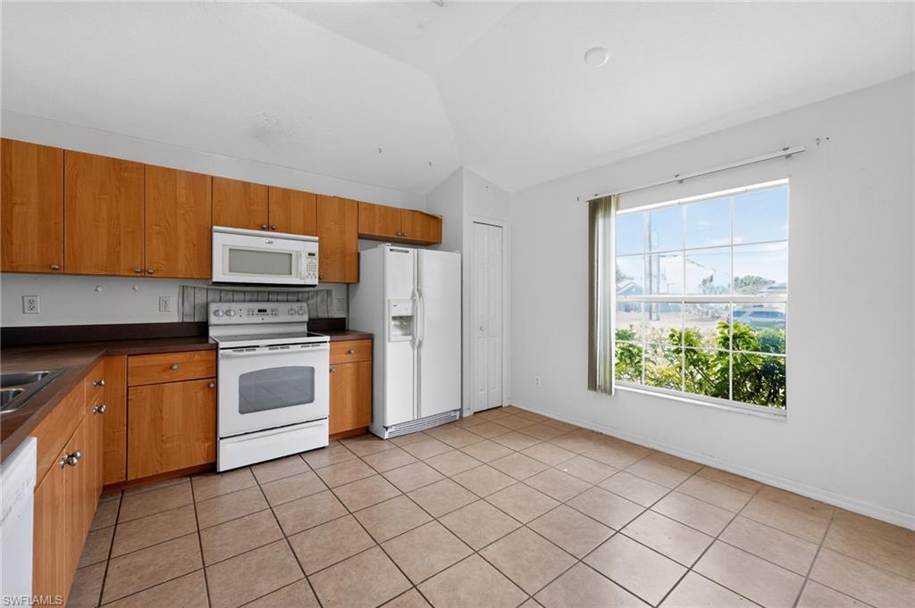 Kitchen featuring wood-finish cabinetry, white appliances, and a large window