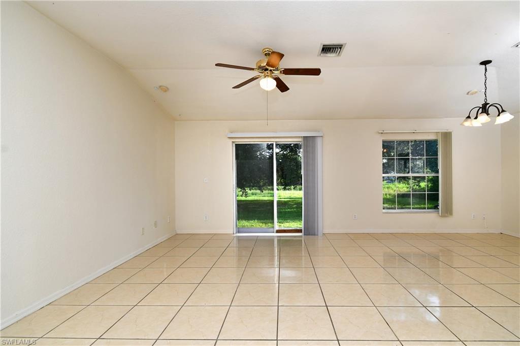 Spacious interior featuring large format tile flooring, vaulted ceilings, and a ceiling fan