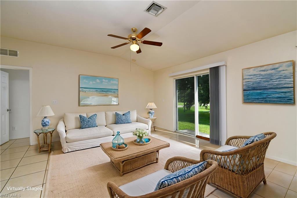 Living area featuring vaulted ceilings with a ceiling fan, light-toned tile flooring, and sliding glass doors to the exterior