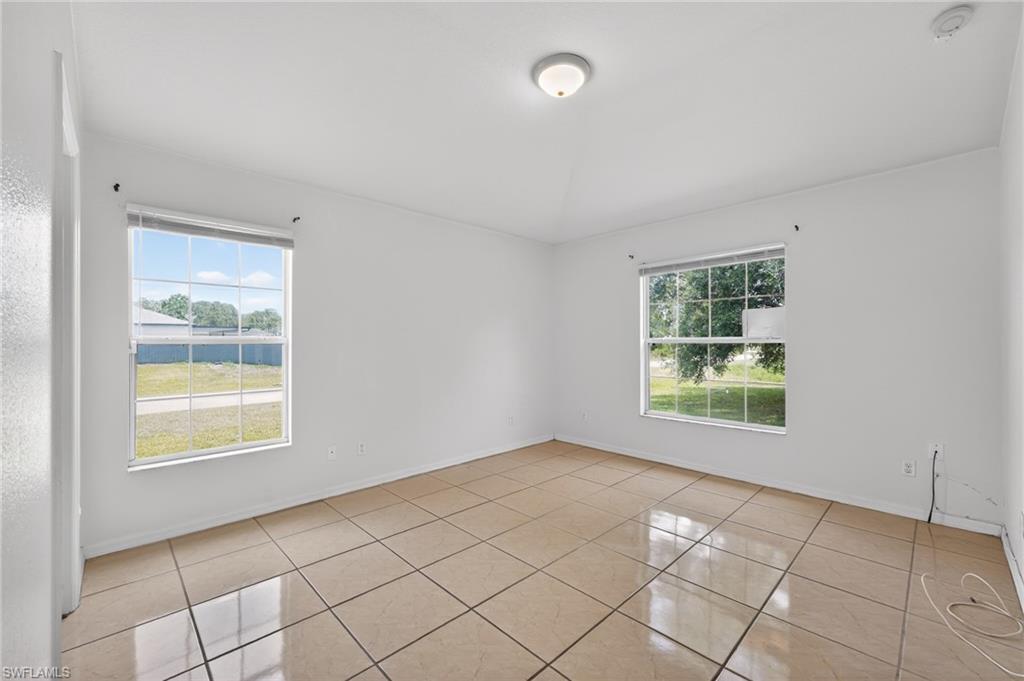 Spacious room featuring tile flooring, white walls, and two large windows