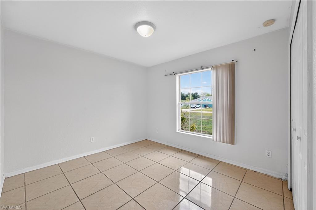 Room featuring ceramic tile flooring, a large window, white walls, and a ceiling-mounted light fixture