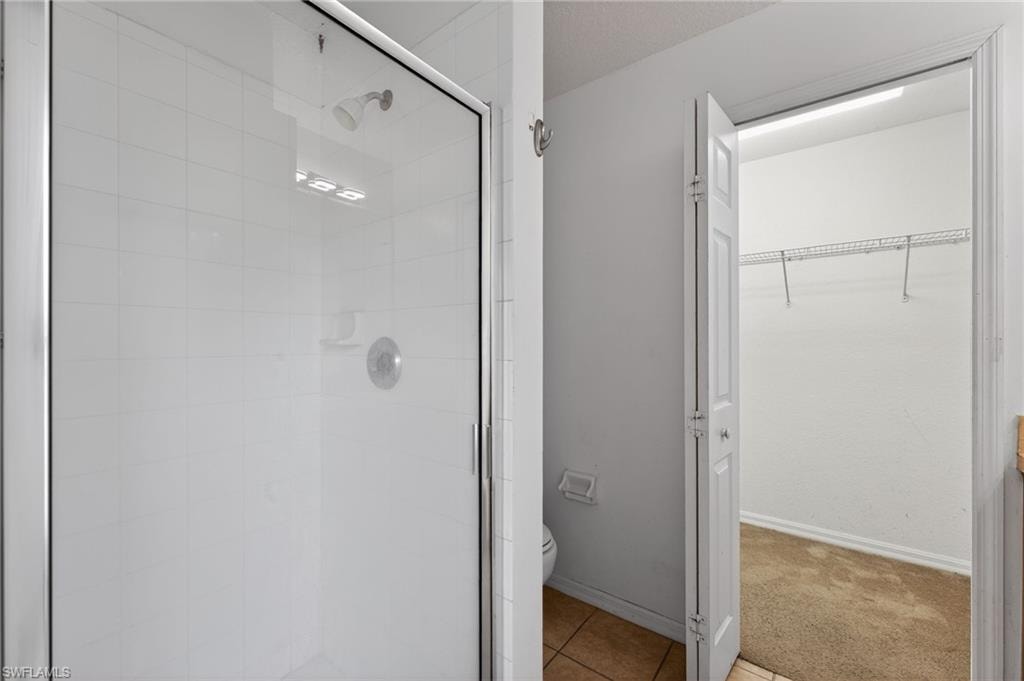 Glass-enclosed shower with white tiled walls and a chrome showerhead
