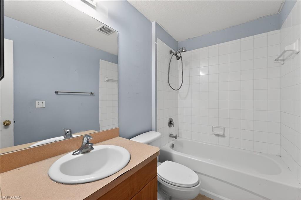 Bathroom with a built-in wood-finish vanity, integrated sink, and chrome faucet
