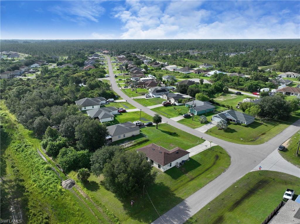 Aerial perspective of a residential street with single-story homes, surrounded by natural landscaping