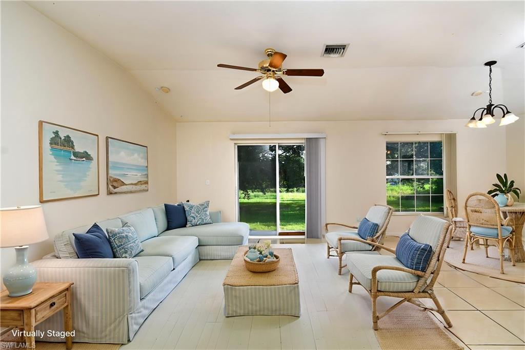 Open-concept living space featuring light-toned flooring, a ceiling fan with integrated lighting, and multiple windows