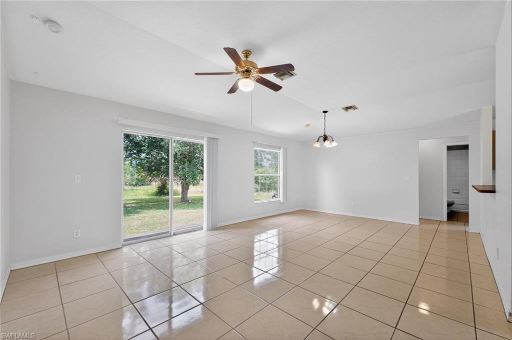 Spacious room featuring neutral tile flooring, white walls, and a ceiling fan