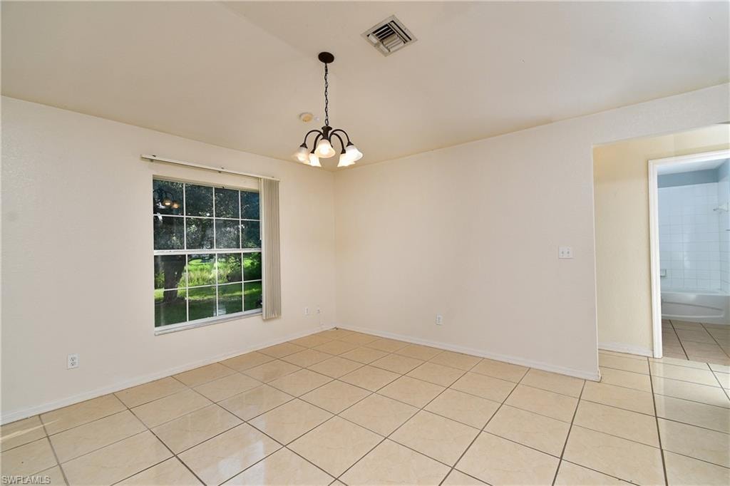 Spacious interior room featuring light-toned tile flooring, a multi-pane window, and a five-light chandelier