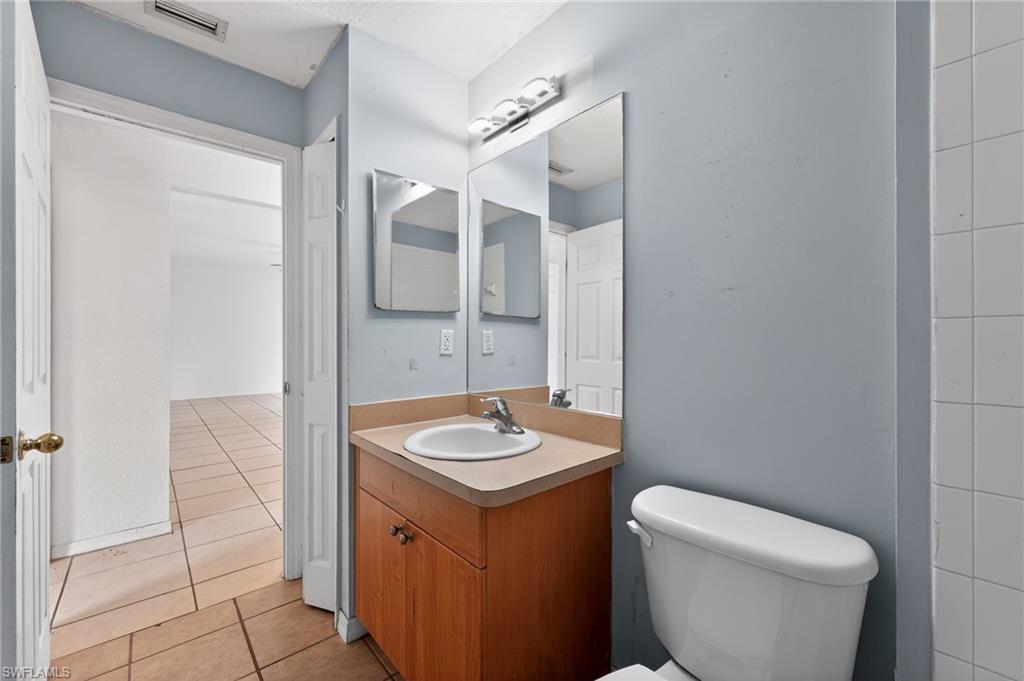 Bathroom vanity with a white ceramic sink, light-colored countertop, and wood-finish cabinetry