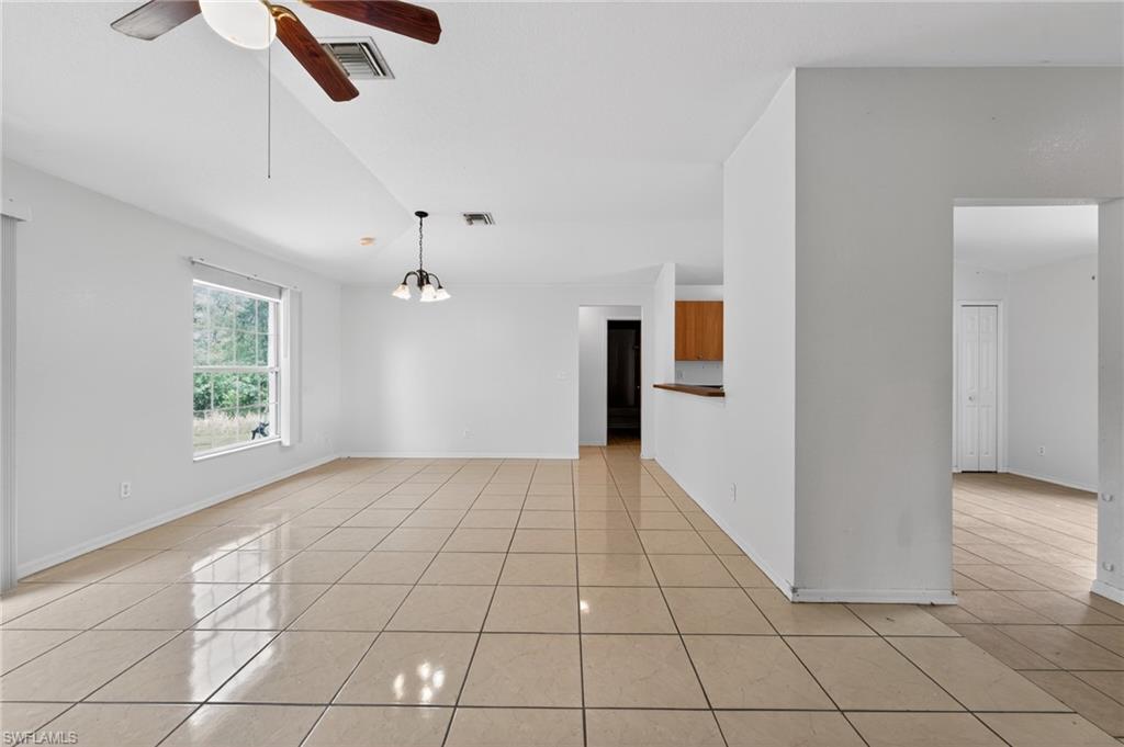 Spacious room featuring tile flooring, a ceiling fan, a window providing exterior views, and a pendant light fixture