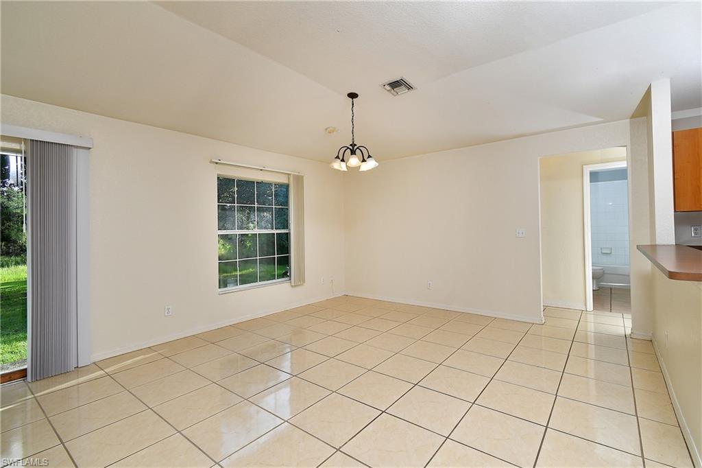 Spacious room featuring neutral-toned tile flooring, a large window, and a sliding glass door