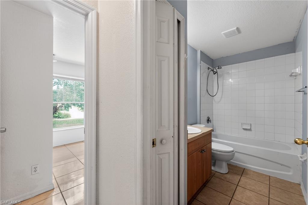 Bathroom featuring a white subway tile tub surround, white bathtub, and wood-finish vanity with an integrated sink