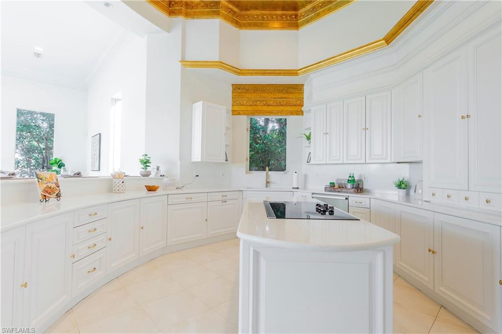 Kitchen featuring a high ceiling, white cabinets, a center island, black electric stovetop, and crown molding