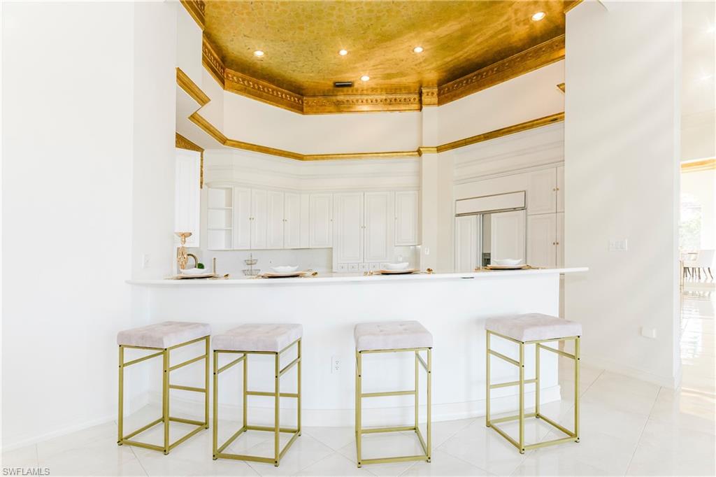 Kitchen featuring a raised ceiling, a breakfast bar, a high ceiling, and white cabinetry